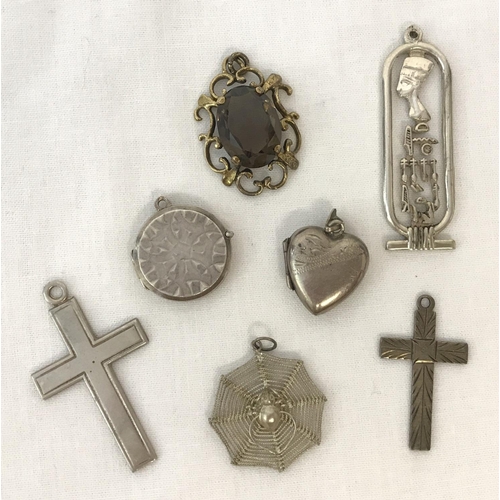 15 - 7 silver and white metal pendants. A drop pendant with Egyptian hieroglyphs, a spiders web with spid... 