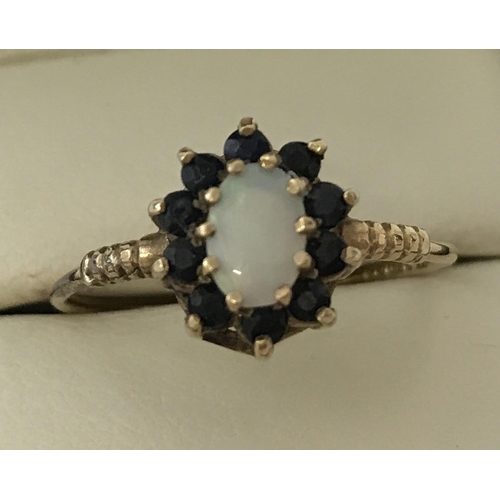 53 - A 9ct gold sapphire and opal dress ring. Central oval cut opal surrounded by 10 small sapphires. Rin... 