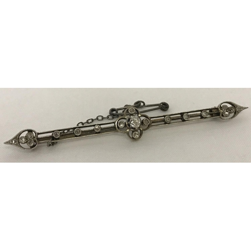6 - An Edwardian diamond set bar brooch with safety chain. Tests as 14ct gold. Total of 21 diamonds of v... 