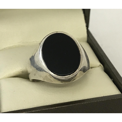 1139 - A men's silver signet ring set with an oval black onyx stone. Size T.  Total weight approx. 6.9g.