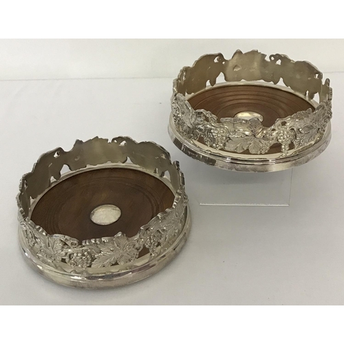 1199 - 2 heavy silver plated wooden based coasters with grape and vine detail to sides.  Approx. 4.75cm tal... 