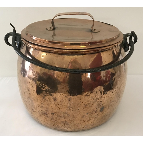 1264 - A very large, antique copper, lidded cooking cauldron with swing handle. Of bulbous form, with rivet... 