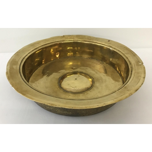 1270 - An antique brass large rimmed bowl with straight sides and domed central panel. Possibly from a chur... 