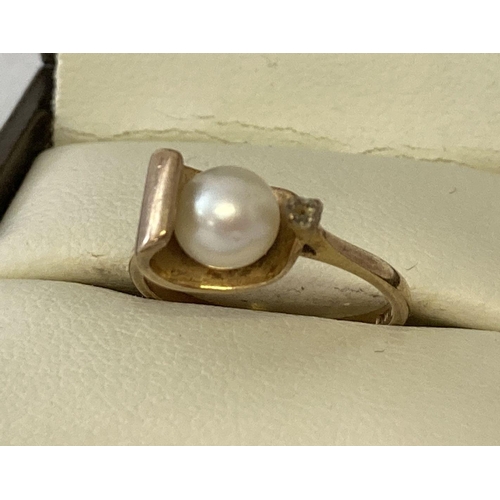 1055 - A contemporary design 9ct gold ring set with a single pearl. With a side mount for a single small ro... 