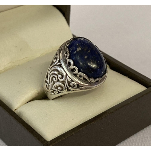 1083 - A silver and oval cut lapis lazuli dress ring. Pierced scroll detail to both sides. Marked 925 to in... 