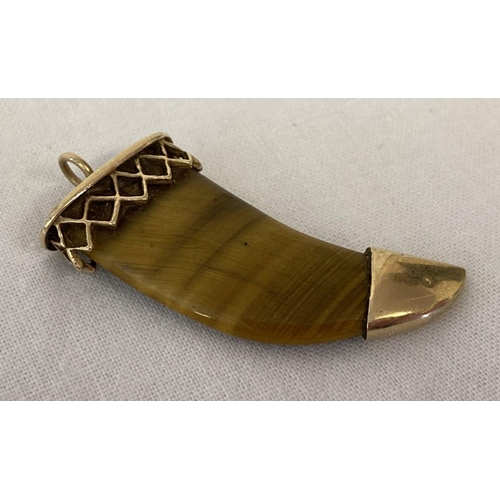 1089 - A 9ct gold and tigers eye pendant in the shape of a tigers tooth. Decorative mount to top, with full... 