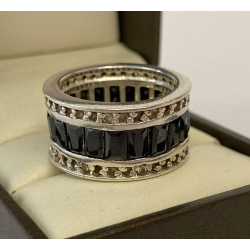 1093 - A heavy silver full eternity style band ring set with baguette cut black stones. Framed by small rou... 