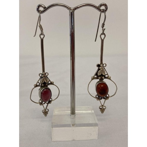 1107 - A pair of Art Nouveau style silver drop earrings set with garnet cabochon stones. Floral and scroll ... 