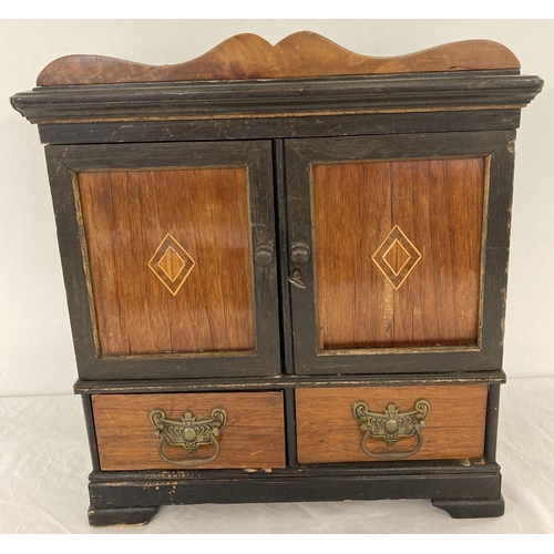 1608 - A small 2 door, 2 drawer cabinet with veneer panelled door fronts. In ebonised and natural wood fini... 