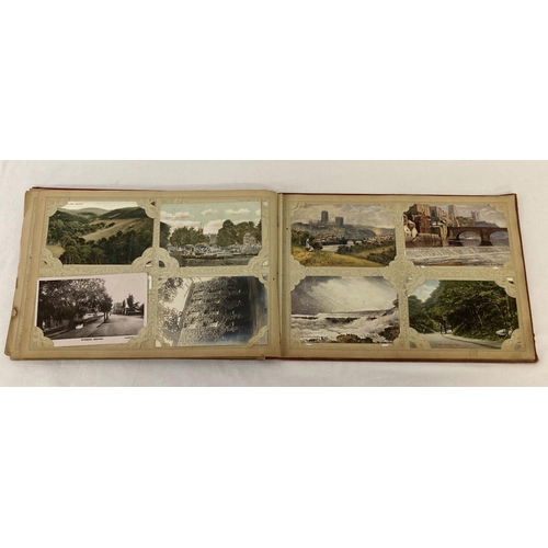 148 - A vintage red postcard album containing approx. 100 assorted vintage postcards.