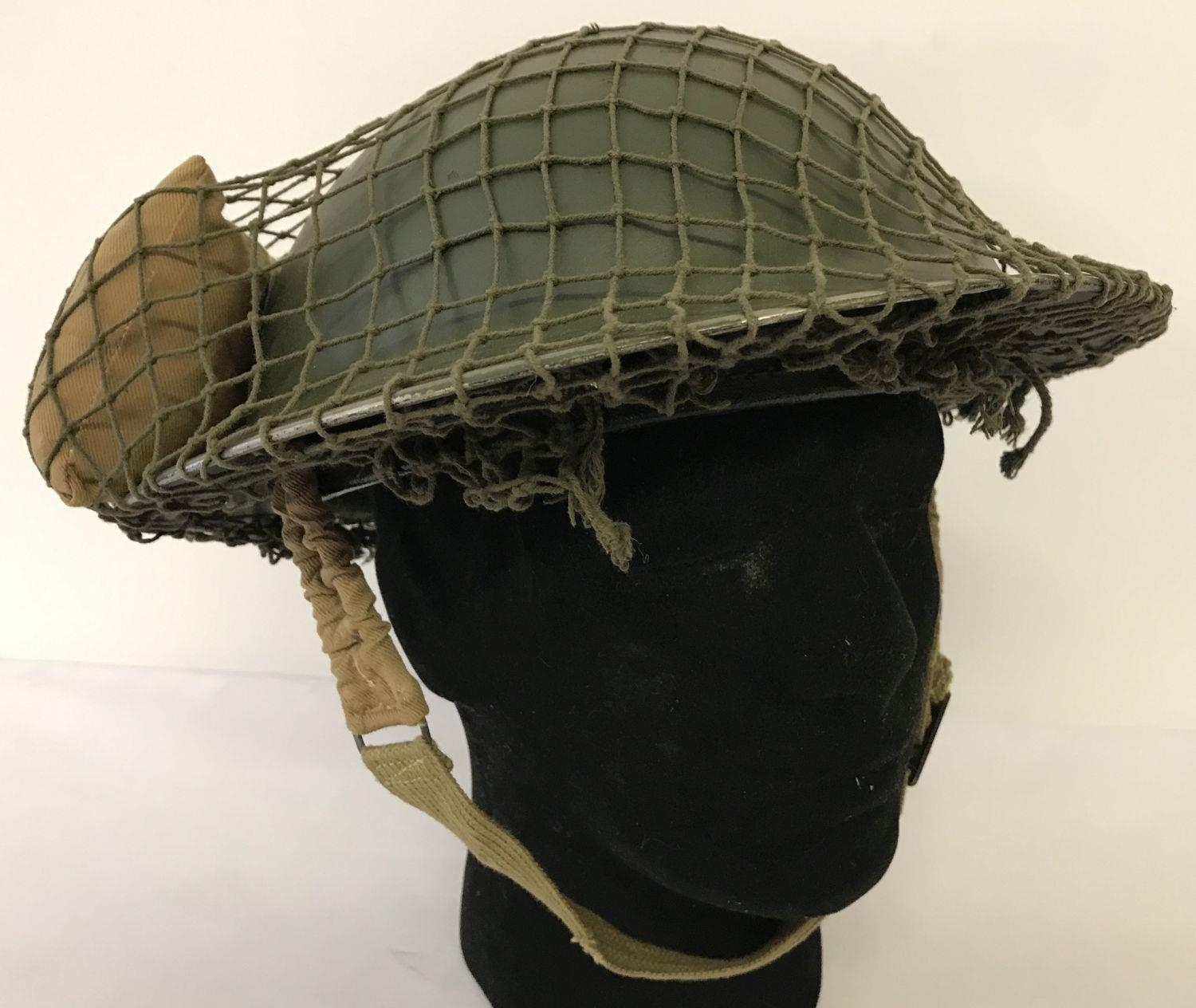 A WWII style British Brodie helmet with cam net and field dressing