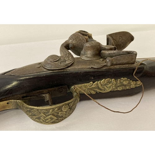 181 - A pair of antique Middle Eastern brass framed flintlock pistols with ornate foliate designs.   Appro... 