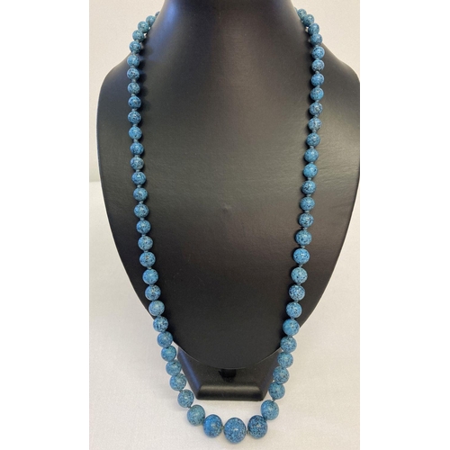 53 - A long graduating turquoise bead necklace with vintage white metal clasp.  Necklace is knotted betwe... 
