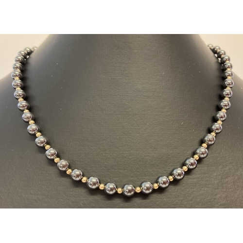 1028 - An alternating hematite and small gold tone bead necklace with 9ct gold spring clasp.  Clasp marked ... 