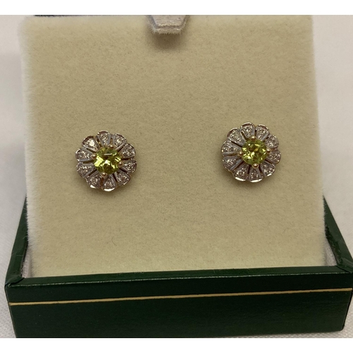 1022 - A pair of 9ct gold stud earrings set with peridots & diamonds by Luke Stockley, London Simple flower... 