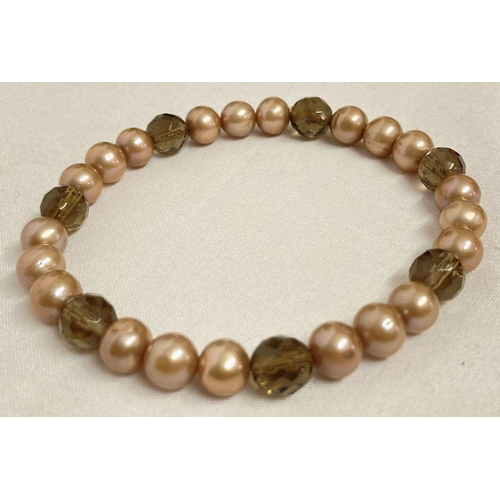 1035 - A pearl and smoked quartz expanding bracelet. Natural pale coffee coloured pearls with facet cut smo... 
