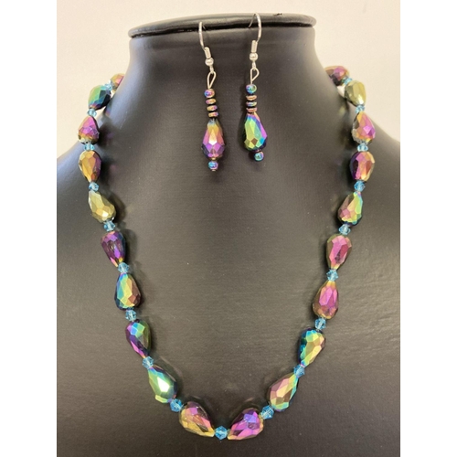 1047 - A faceted iridescent lustre glass beaded necklace with matching drop earrings. Necklace has silver t... 