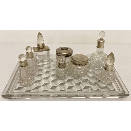 1121 - A moulded glass vanity tray with a collection of silver collared perfume bottles and vanity jars. Va... 
