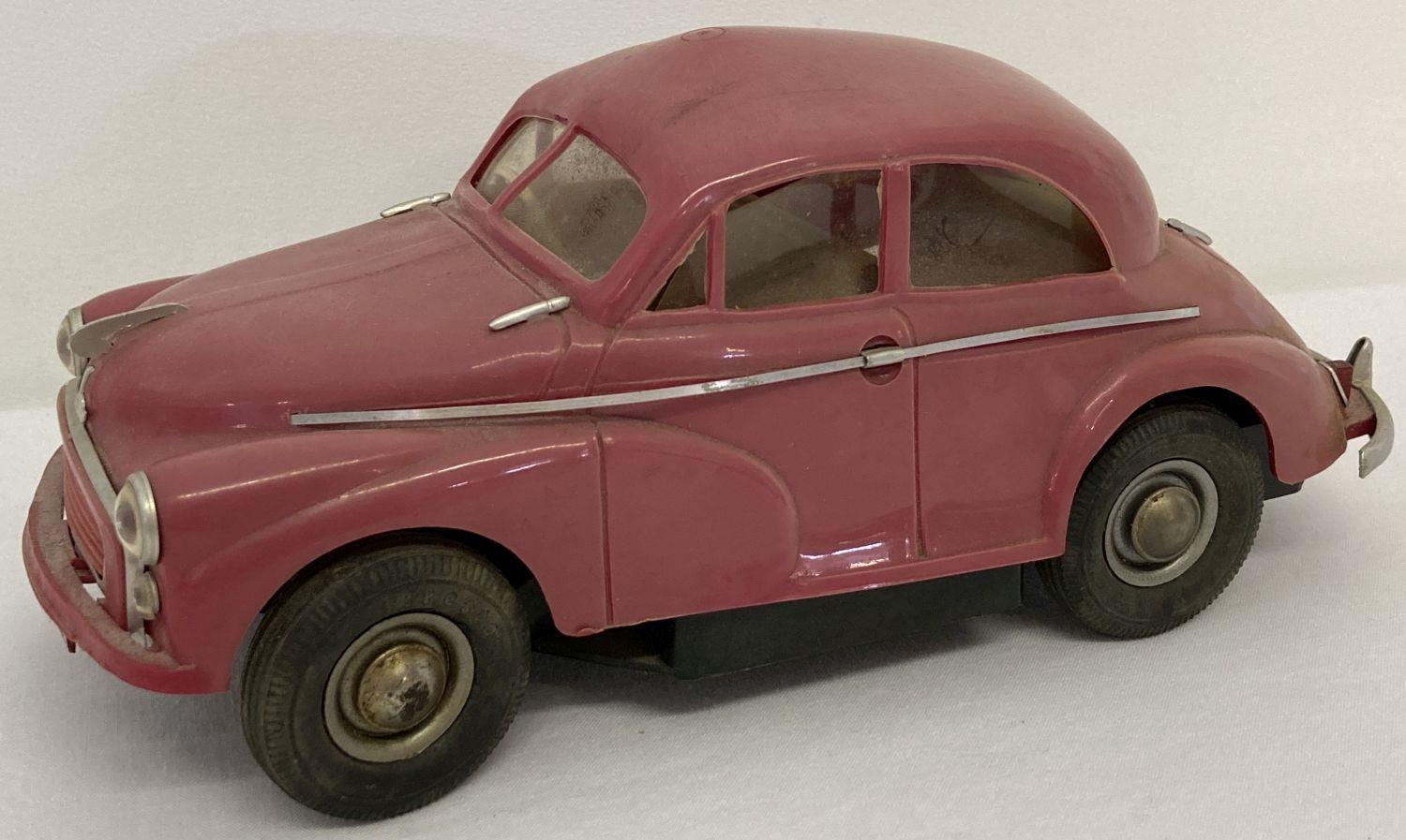 A vintage Victory Industries 1954 red pink plastic battery operated Morris Minor toy car. Produced t