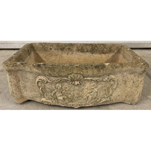 1355 - A stone trough style garden planter with carved cherubs and floral detail to front. Drainage hole to... 