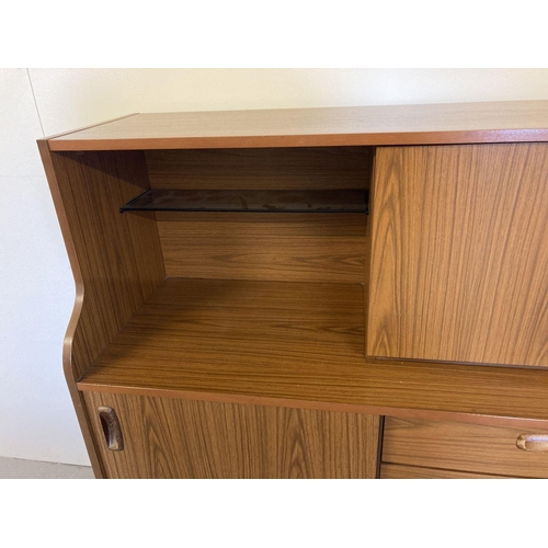 71 - A vintage mid century Schreiber teak sideboard with sliding doors, drawers and glass shelves. Raised... 