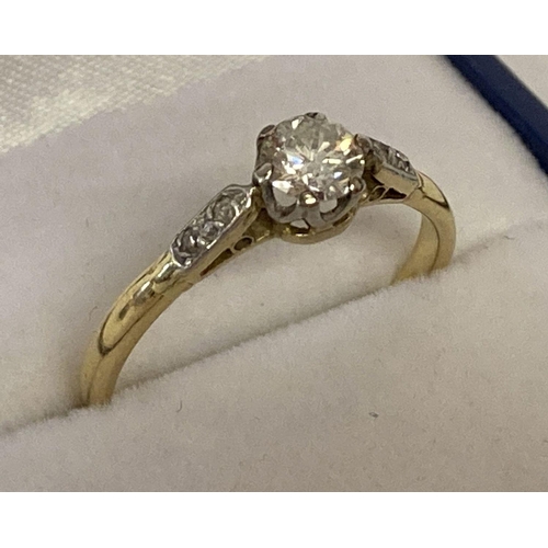 1013 - A vintage 18ct gold diamond solitaire dress ring. A central .25ct round cut diamond with 2 small rou... 