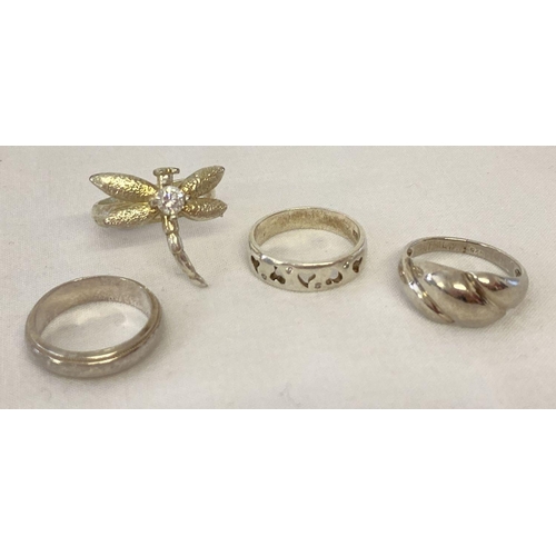 1019 - 4 silver and white metal dress rings. Comprising: band ring, a dragonfly ring set with a clear stone... 