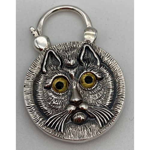 32 - A double sided silver pendant with opening bale. Carved cats face detail to one side and round bande... 