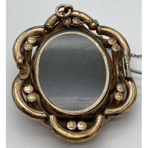 27 - A large Victorian mourning brooch with rotating central panel and pinchbeck mount. Swivel panel feat... 