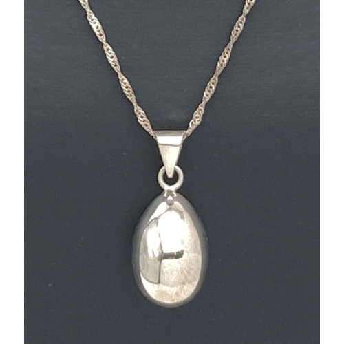 64 - A silver egg shaped chiming pendant on an 18 inch Singapore style chain. Bale to pendant marked 925.... 