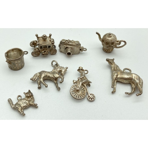 71 - 8 vintage silver and white metal charms. A horse, a man riding a penny farthing cycle, a teapot (ope... 