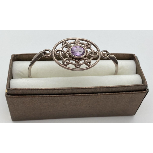 78 - A modern design silver bangle with pierced work panel set with an oval cut amethyst stone. Hook and ... 