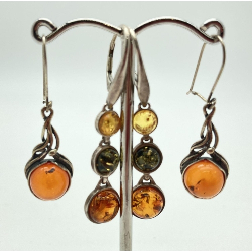 91 - 2 pairs of silver and amber drop style earrings. A decorative pair set with round dark cognac amber ... 