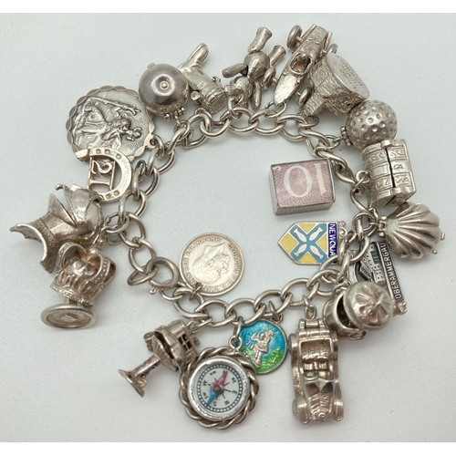 92 - A vintage silver charm bracelet with 21 silver and white metal charms. Many charms open to reveal ch... 