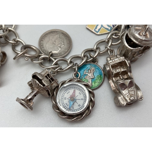 92 - A vintage silver charm bracelet with 21 silver and white metal charms. Many charms open to reveal ch... 