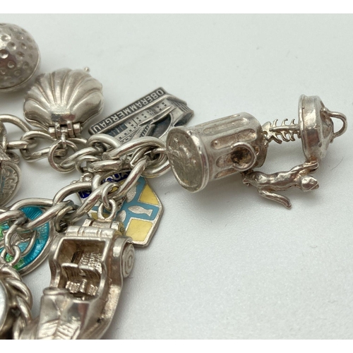 92 - A vintage silver charm bracelet with 21 silver and white metal charms. Many charms open to reveal ch... 