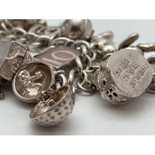 92 - A vintage silver charm bracelet with 21 silver and white metal charms. Many charms open to reveal ch... 