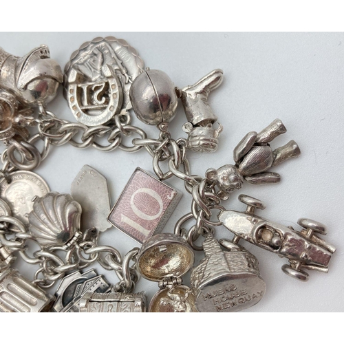 92 - A vintage silver charm bracelet with 21 silver and white metal charms. Many charms open to reveal ch... 