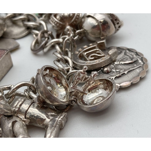 92 - A vintage silver charm bracelet with 21 silver and white metal charms. Many charms open to reveal ch... 