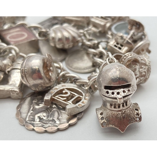 92 - A vintage silver charm bracelet with 21 silver and white metal charms. Many charms open to reveal ch... 