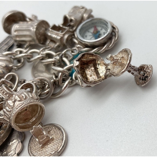 92 - A vintage silver charm bracelet with 21 silver and white metal charms. Many charms open to reveal ch... 