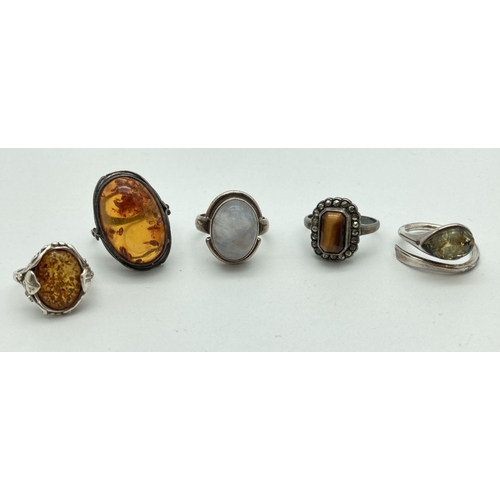 98 - 5 natural stone set silver rings in varying sizes and styles. To include 3 amber set rings, a moonst... 