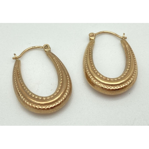 131 - A pair of 9ct gold decorative hollow oval hoop earrings. Posts marked 375. Total weight 1.8g.