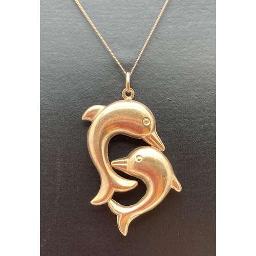 138 - A 9ct gold double dolphin pendant on an 18