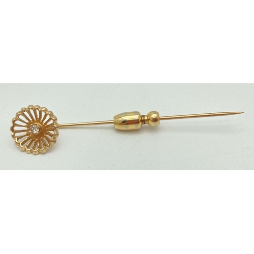 145 - A gold stick pin with flower detail to top set with a small central round cut diamond. Tests as 9ct ... 