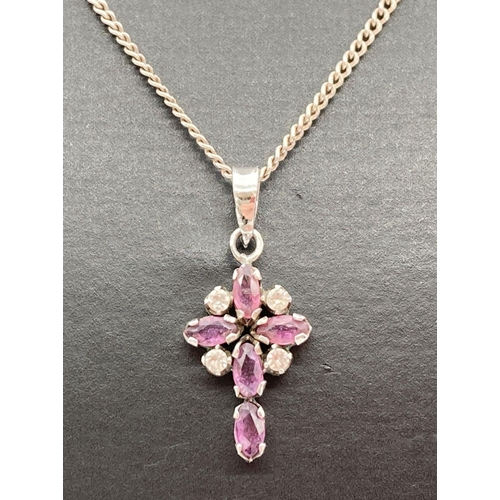 168 - A silver, ruby and clear stone set cross pendant on an 18