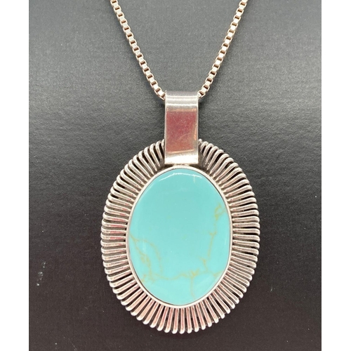 175 - A contemporary design Mexican silver oval shaped pendant set with turquoise. On an 18