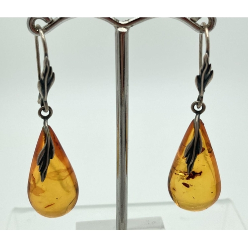 179 - A pair of white metal amber drop earrings with leaf detail to hooks and top of earring. Amber drop a... 