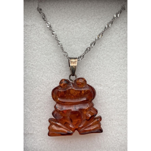 182 - A carved cognac amber pendant in the shape of a frog, on an 18