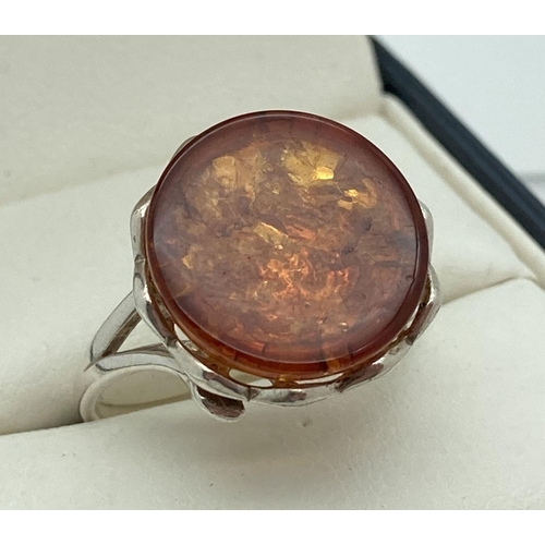 187 - A modern design silver and amber dress ring by The Genuine Gem Company. A cabochon of amber in a pie... 